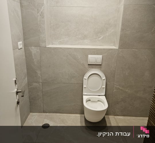 אסלה לבנה על רקע קיר ורצפה אפורים